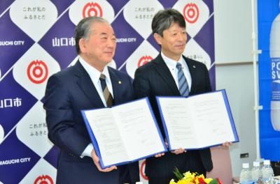 協定書を手に記念写真に納まる前田支店長（右）と渡辺市長（左）