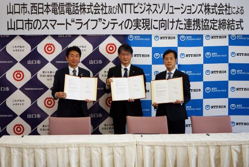 協定書を手にするNTT西日本の中川山口支店長、市長、NTTビジネスソリューションズ株式会社の増野取締役山口ビジネス営業部長（左から）