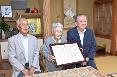 祝状を手に市長と記念撮影をする岡本タツコさん（中央）と息子さんの岡本敏さん（左）
