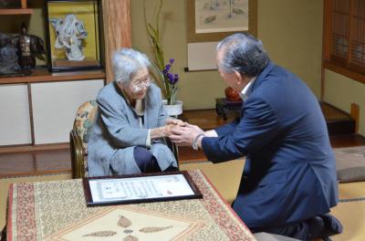 岡本タツコさん（左）の手をとって「今後とも元気で過ごしてください」と声をかける市長