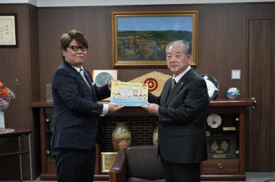 絵本を手渡す川島会長と受け取る渡辺市長