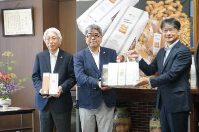 藤井公代表取締役社長（左）と藤井一正代表取締役社長（中央）が市長（右）に商品を手渡す様子