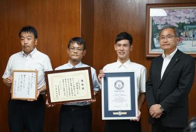 記念撮影の様子（左から、川西中学校村瀨校長、日高雅裕さん、煌人さん、藤本教育長）