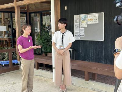 認知症カフェについて紹介する市職員（右）とリポーター（左）