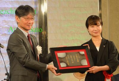 市長（左）から賞状（山口萩焼の陶板）を受け取る佐藤さん（右）