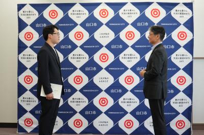 市長（右）の激励を受ける佐伯さん（左）