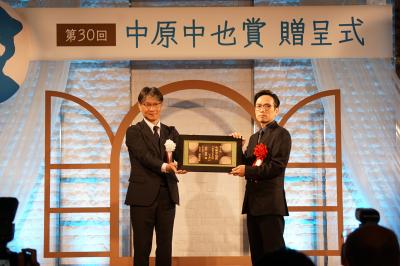 市長（左）から賞状（山口萩焼の陶板）を受け取る高村さん（右）