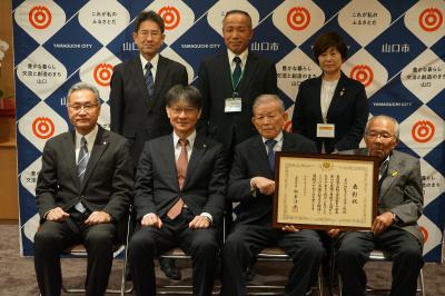 記念撮影の様子（前列右から、平川地区子ども見守り隊の藏成幹也さん、野村学代表、市長）