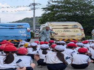 ごみ収集車の説明を児童が聞いている。