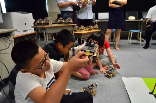 大殿小の児童が作ったロボットを興味津々に眺める済南市の訪問団員
