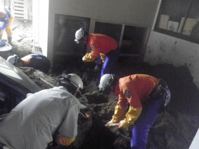 行方不明者の捜索のため、住宅に流れ込んだ土砂をシャベルで取り除く様子
