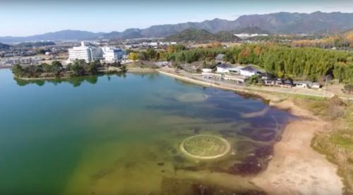 鋳銭司の長沢池上空から池の砂に描かれたサンドアートを撮影している様子