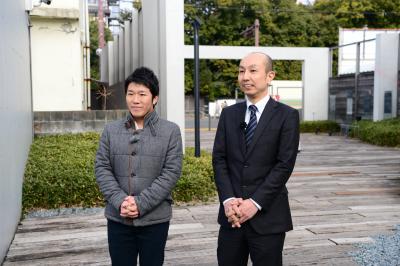 田中亨アナウンサー（左）と学芸員（右）が前庭でいくつかの作品を伝えている様子