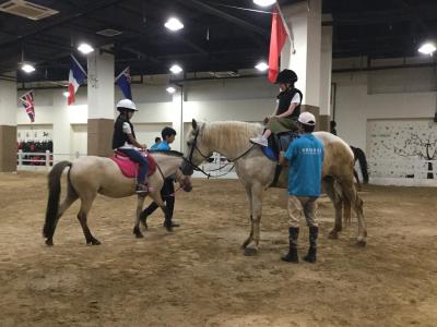 済南市青少年宮の建物内にある馬場で馬術を体験する団員