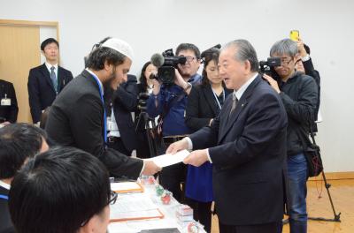 留学生（左）に委嘱状を手渡す市長（右）