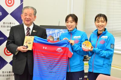 石川佳純選手（中央）と梨良選手（右）からサイン入りのユニフォーム等を受け取る市長（左）