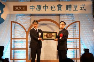 市長（左）から賞状（山口萩焼の陶板）を受け取る高村さん（右）