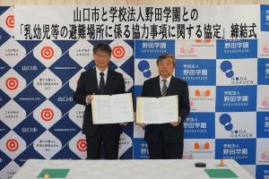協定書を手にする市長（左）と学校法人野田学園の田邉理事長（右）