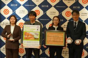 記念撮影の様子（左から、若崎さん、長尾専務、長尾社長、市長）